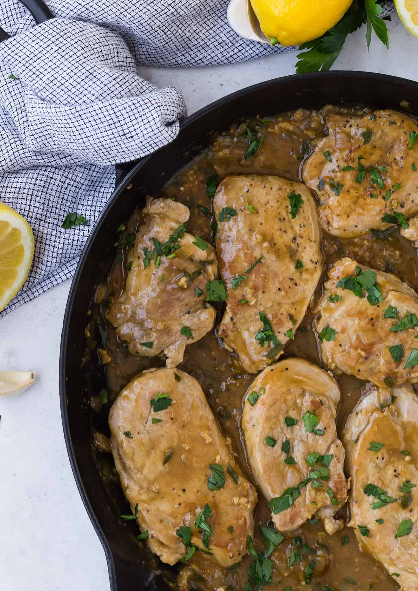 Pork medallions in a black frying pan with sauce.