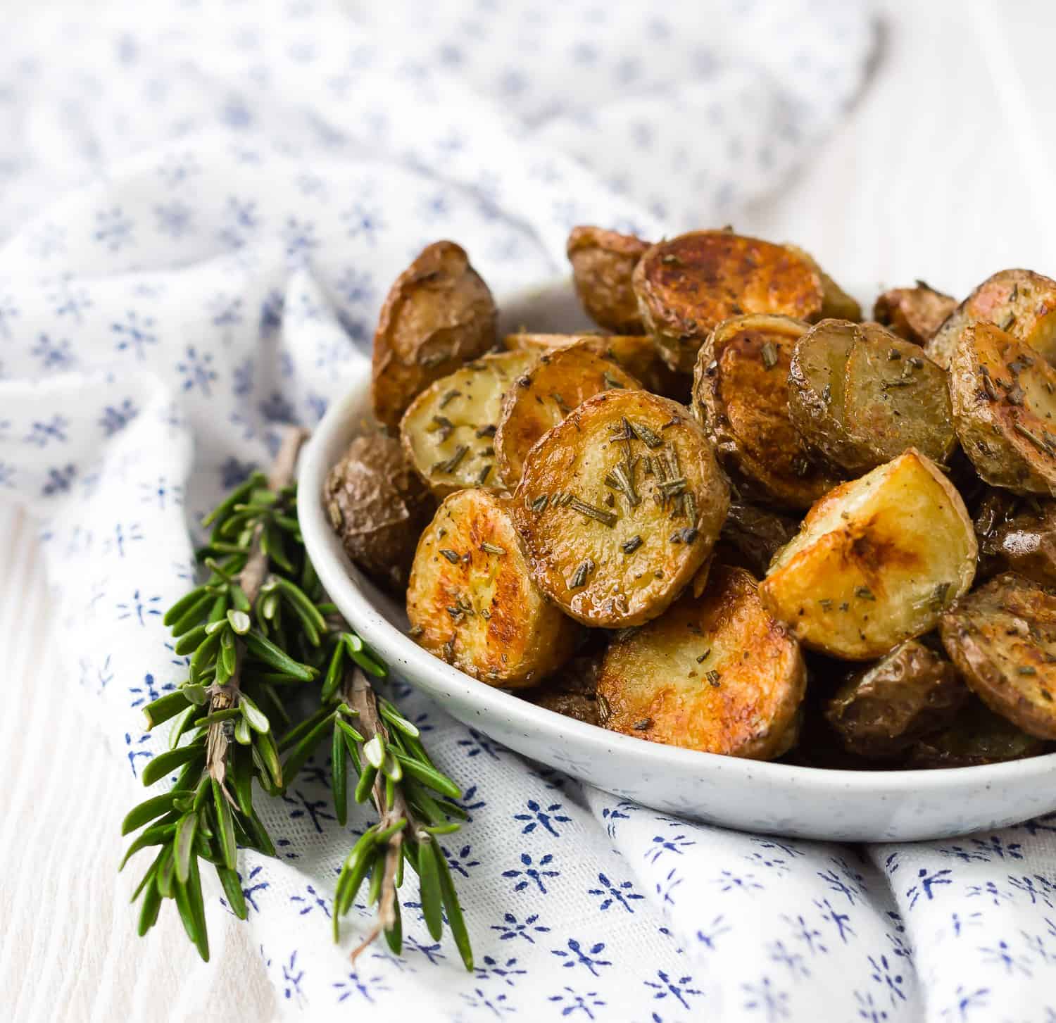 Roasted potatoes with rosemary in small bowl.