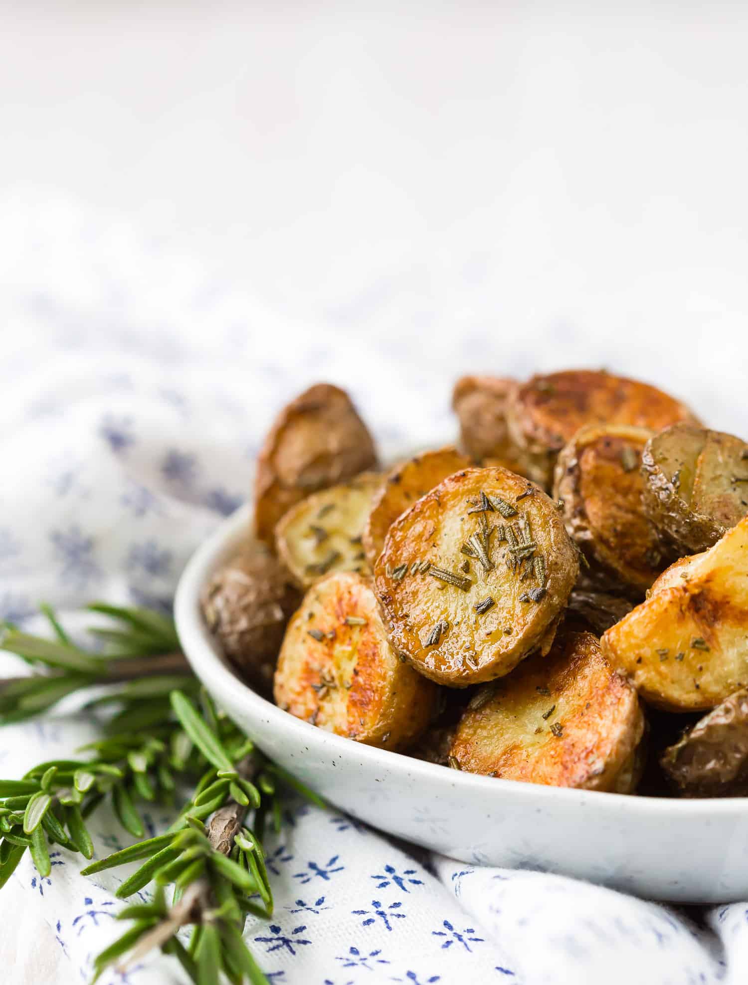 Rosemary roasted potatoes in a small white bowl.