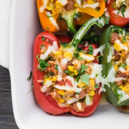 Vegetarian stuffed peppers in white baking dish.