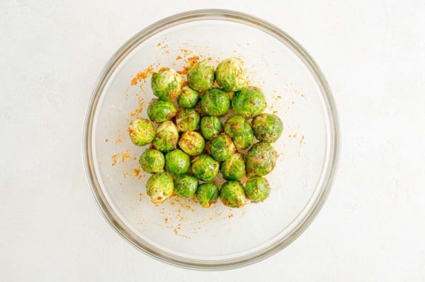 Seasoned microwaved Brussels sprouts in a glass bowl.