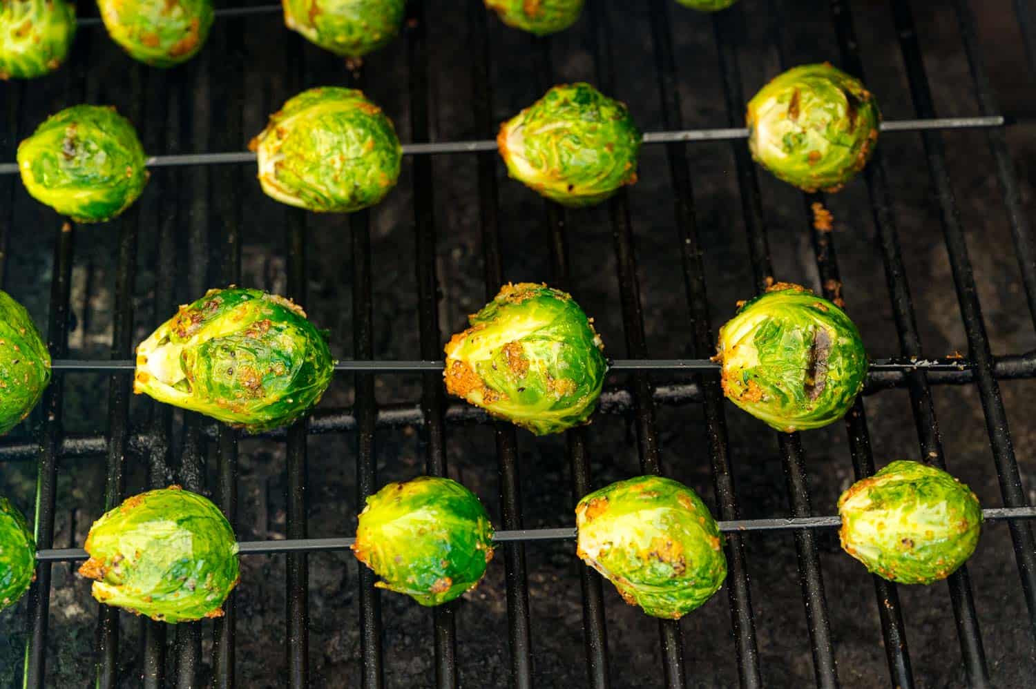 Close up of seasoned Brussels sprouts skewers on a grill.
