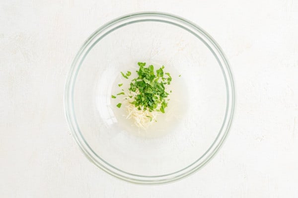 Parmesan, parsley, and lemon juice combined in a glass bowl.