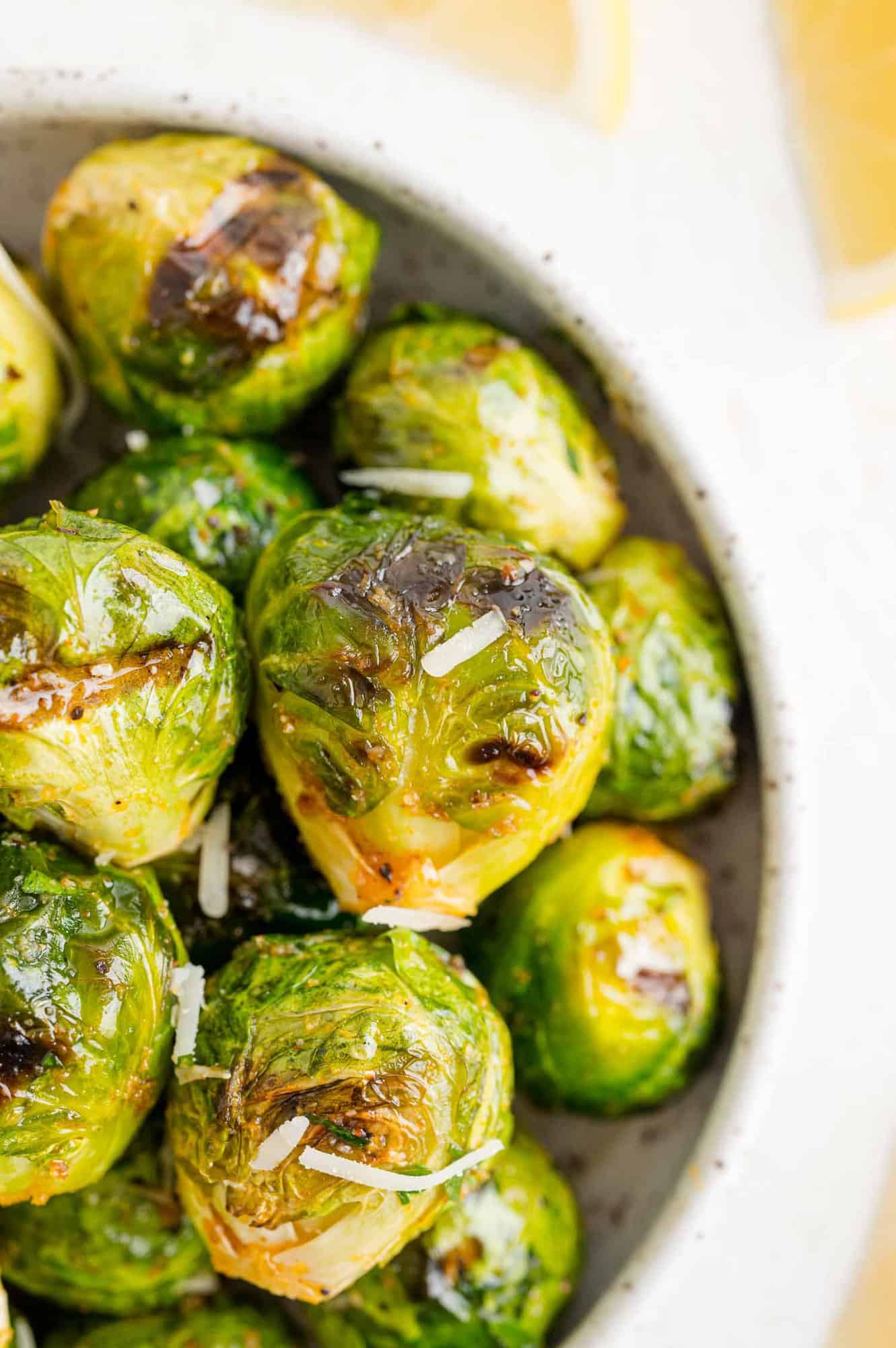 Close up overhead view of a bowl of grilled Brussels sprouts tossed in lemon and parmesan.