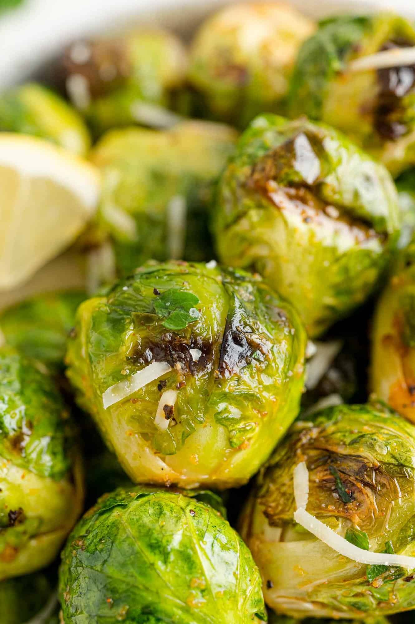 Close up of a bowl of grilled Brussels sprouts tossed in lemon and parmesan.
