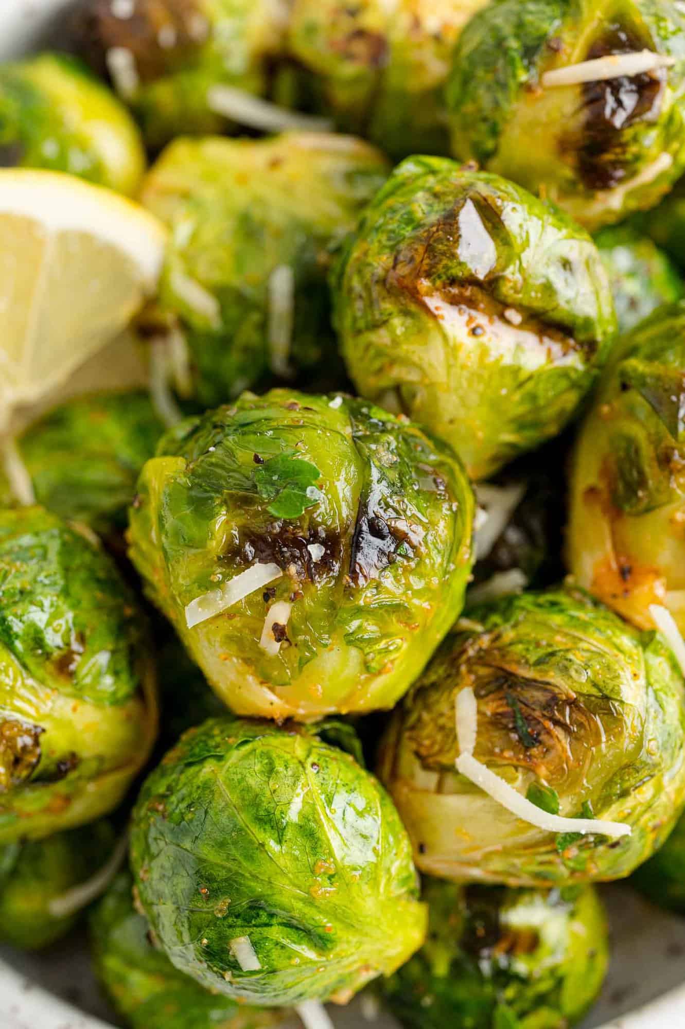 Close up of grilled Brussels sprouts tossed in lemon juice and grated parmesan.