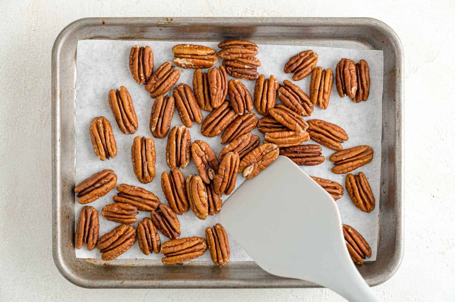 Pecan halves being toasted on a sheet pan.