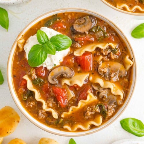 Lasagna soup in bowl with a cheese topping.