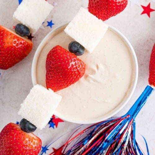 Brochette de fruits patriotique placée sur un bol de trempette au yogourt à la vanille.