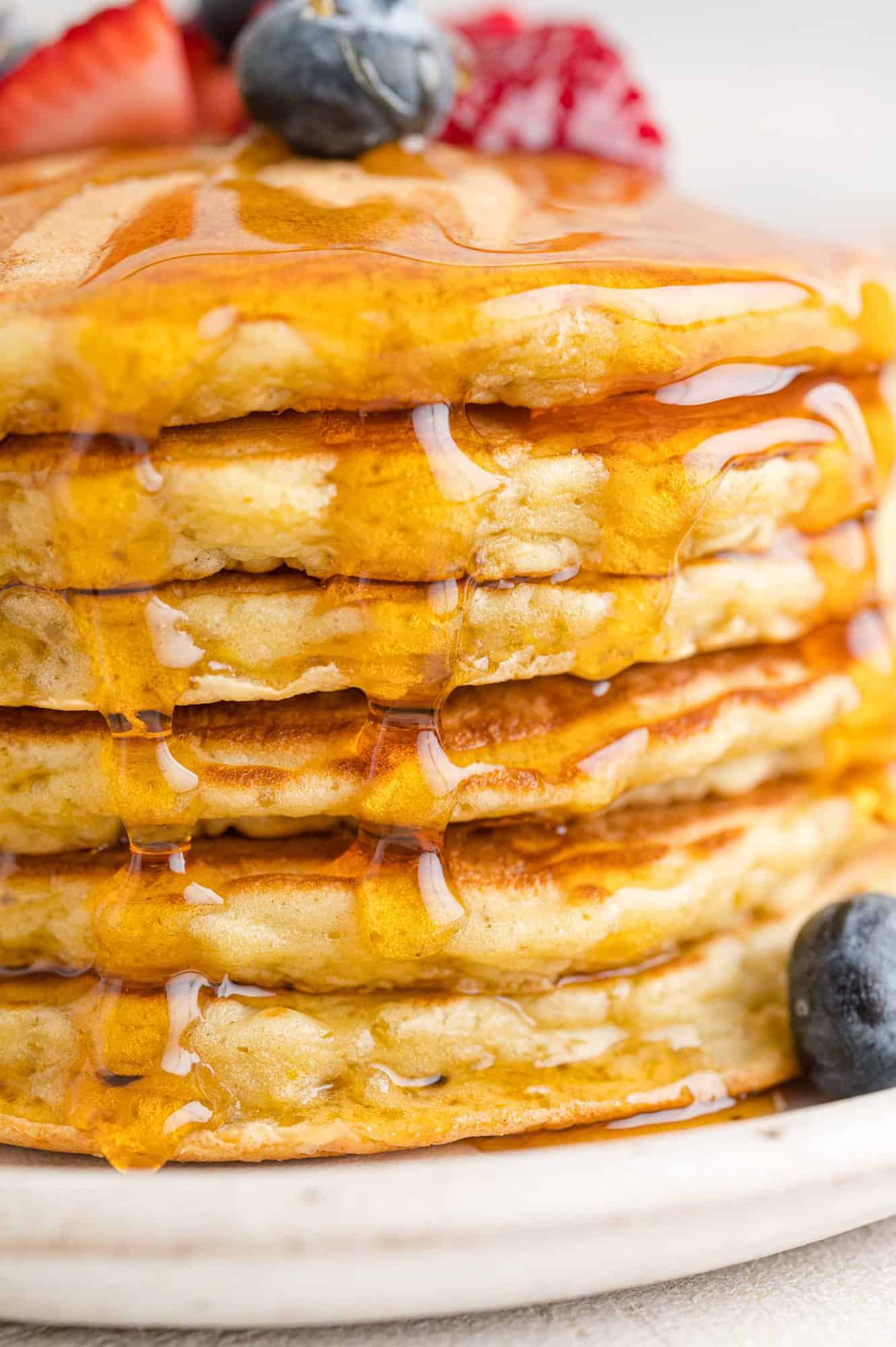 Syrup dripping down stack of quinoa pancakes.