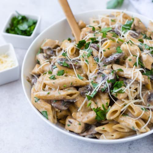 Chicken marsala pasta with a wooden spoon.