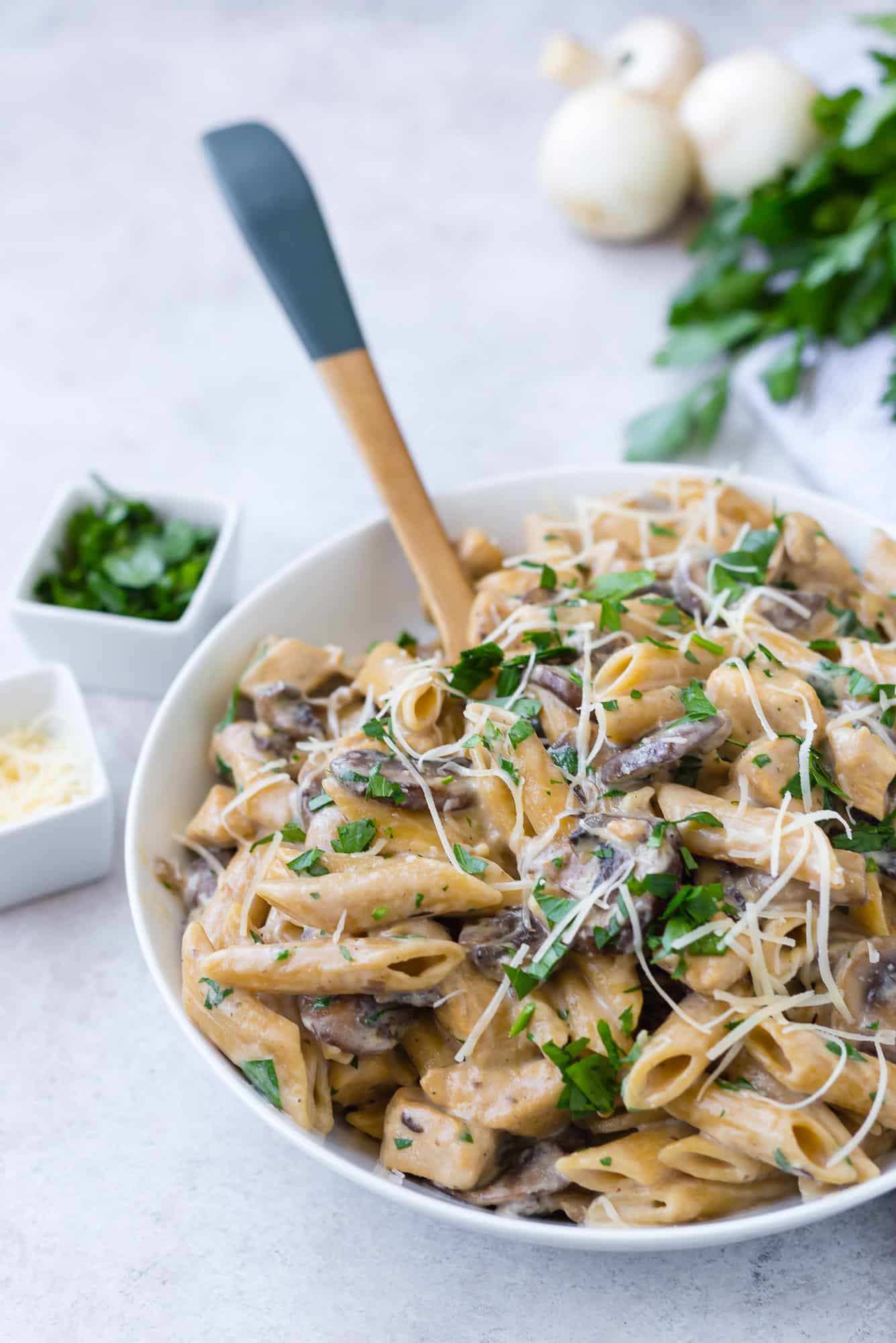 Pasta with chicken and mushrooms in a large white serving bowl.
