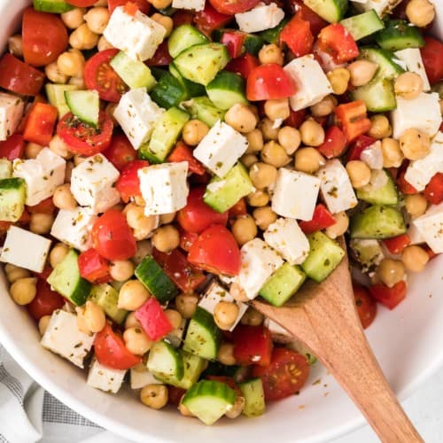 Chopped greek salad with a wooden spoon.