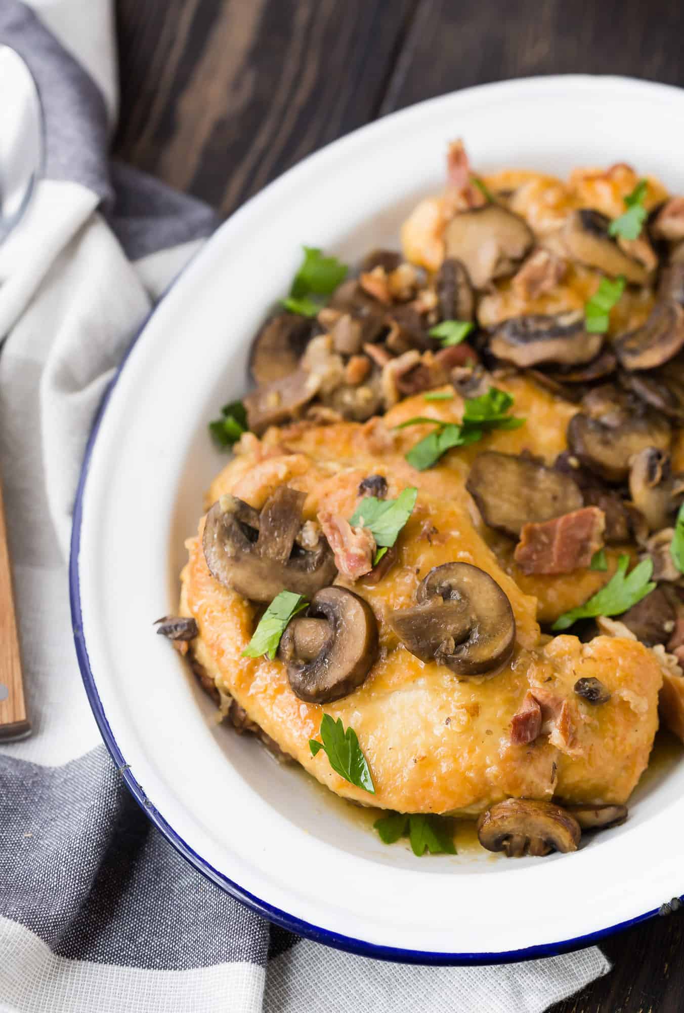 Chicken with mushrooms and parsley on a white platter.