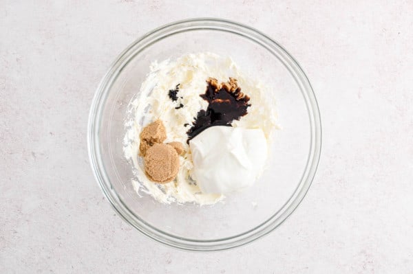 Ingredients for cream cheese fruit dip added to a mixing bowl with beaten cream cheese.