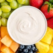 Overhead view of a bowl of cream cheese fruit dip in the center of a fruit platter with assorted fruits and berries.