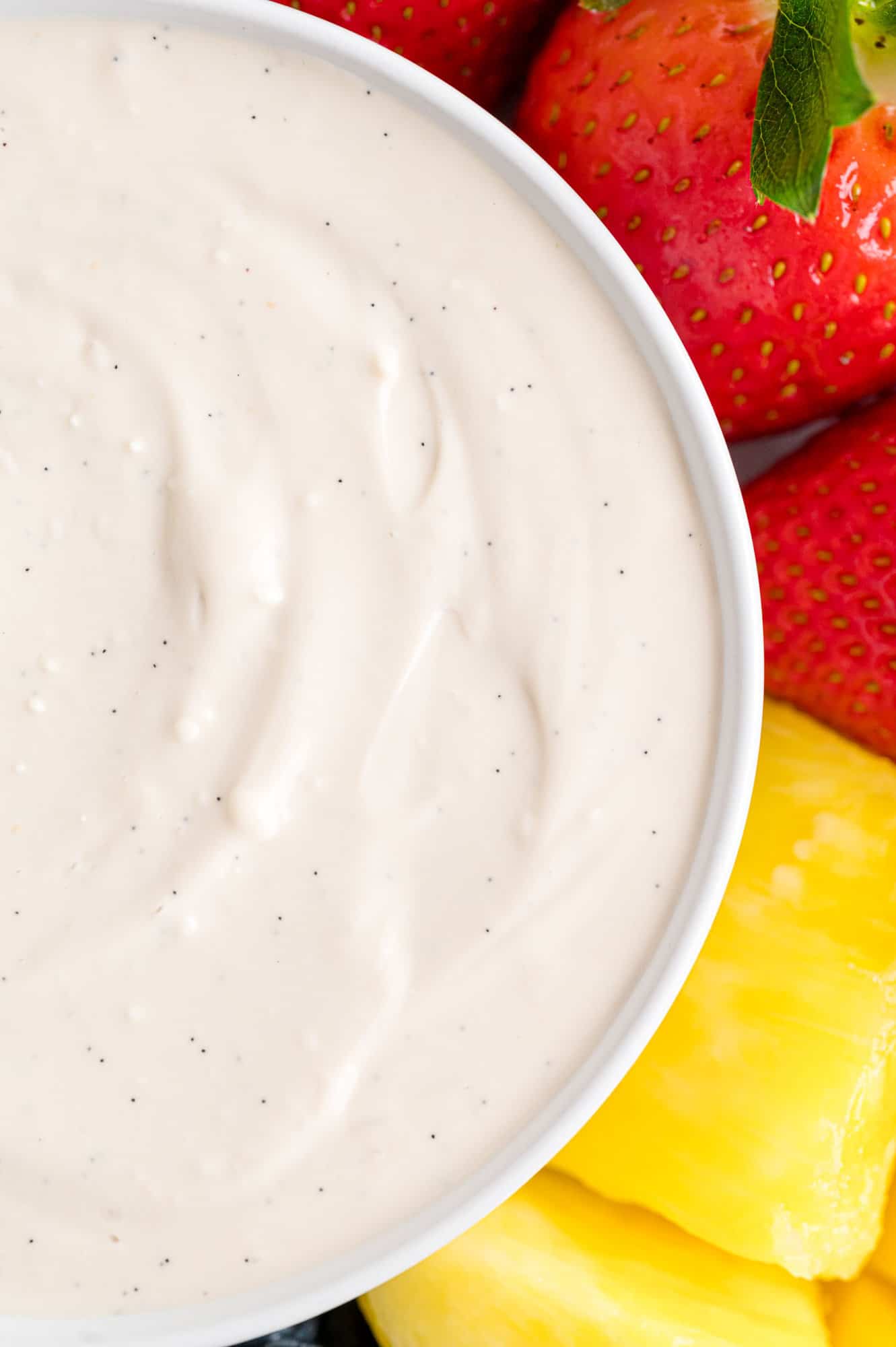 Close up of a bowl of cream cheese fruit dip next to assorted fruit.