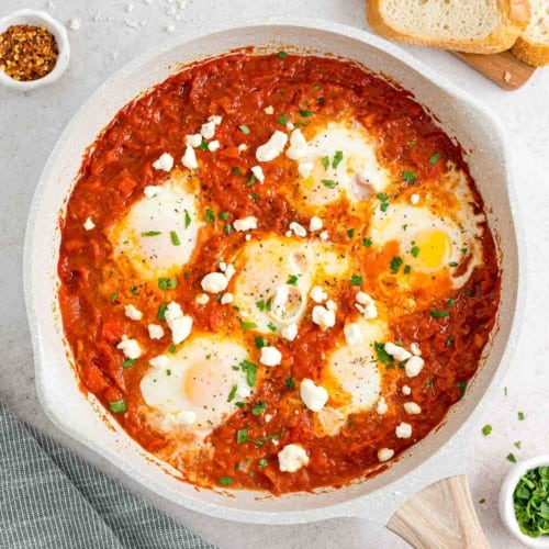 Shakshuka in a white skillet topped with feta cheese.