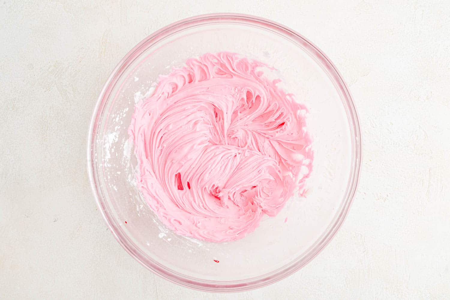 Pink buttercream frosting in a mixing bowl.