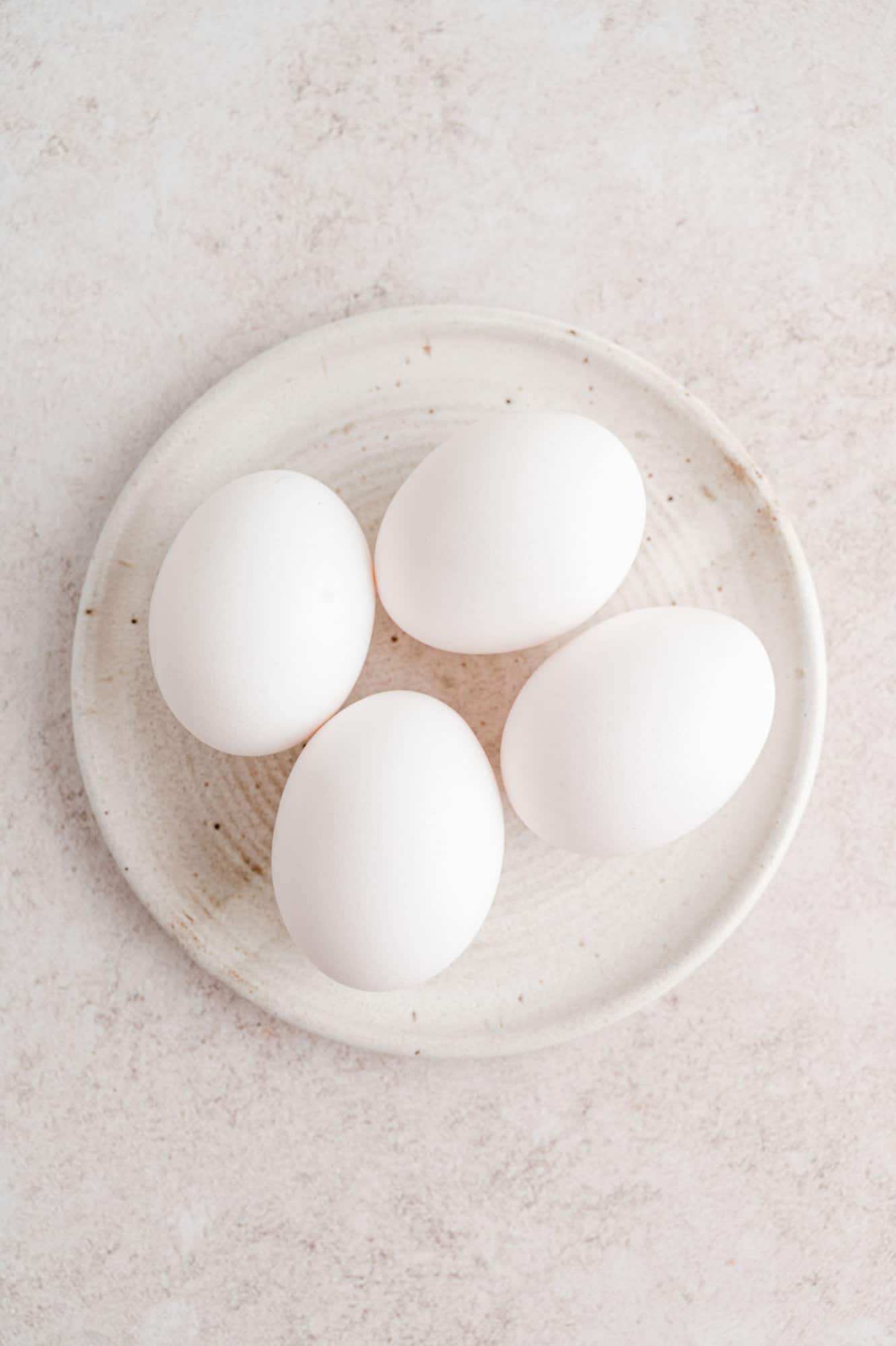 The air fryer is the best way to “boil” eggs that come out perfectly every time! Use this easy method for jammy, soft, or hard-boiled eggs. Overhead view of four eggs on a white plate.