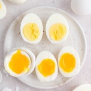 Air fryer boiled eggs on a plate, cut in half to reveal yolks cooked to varying doneness.