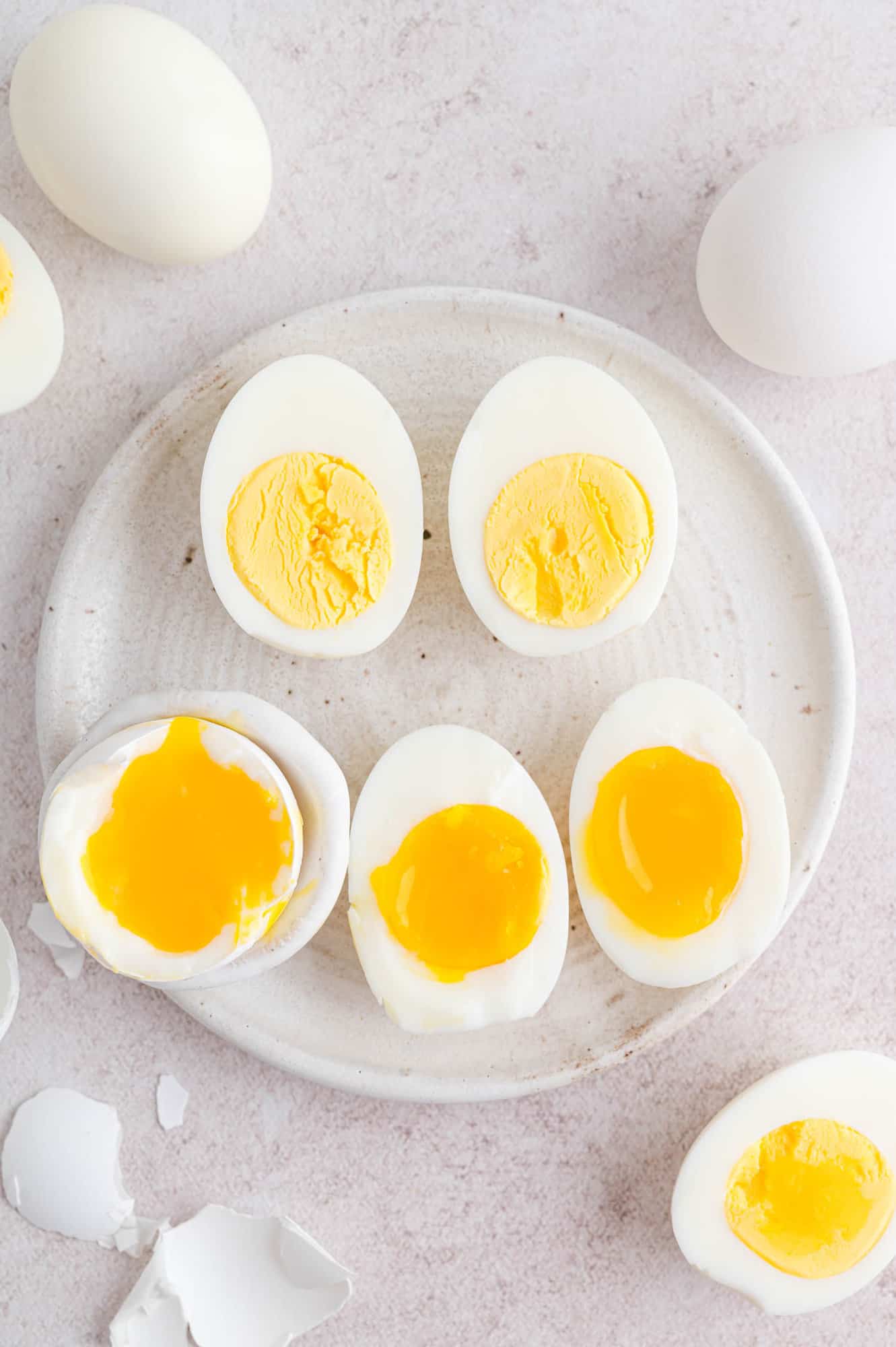 Air fryer boiled eggs on a plate, cut in half to reveal yolks cooked to varying doneness.