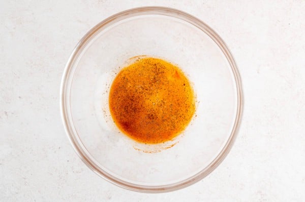 Oil and seasonings in a glass bowl.