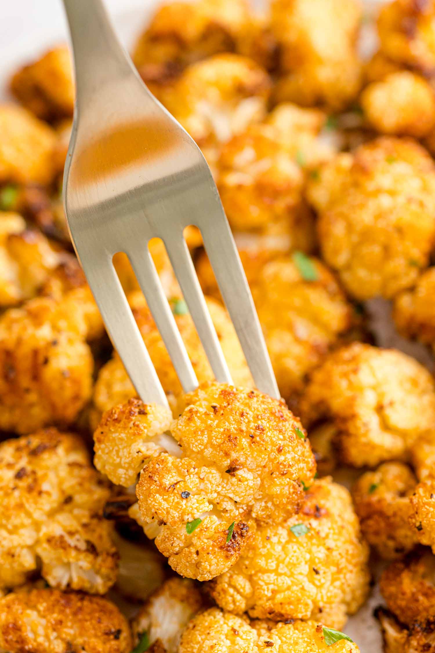 A fork stuck into a piece of air fried cauliflower.