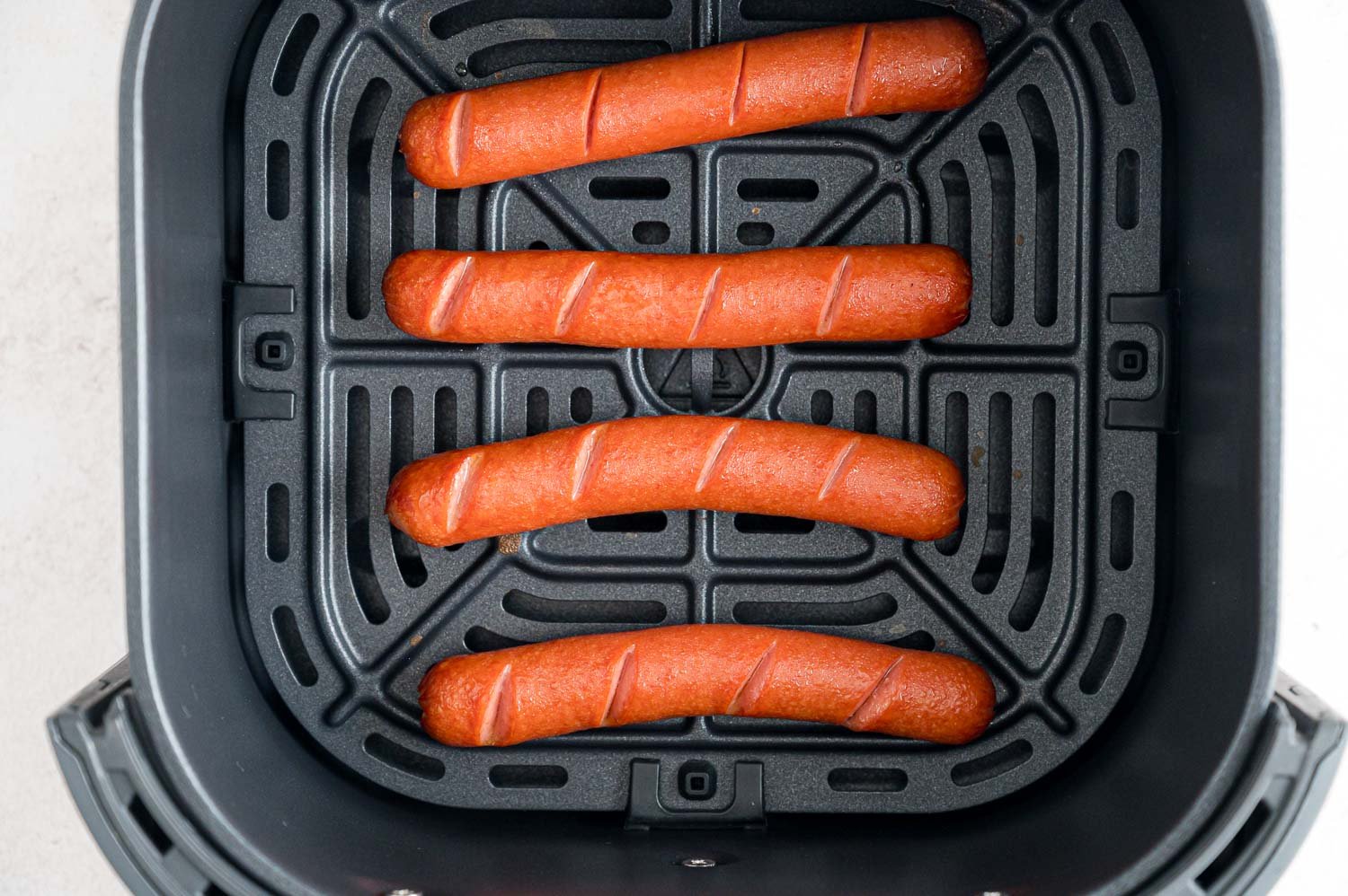 Cooked hot dogs in the air fryer basket.