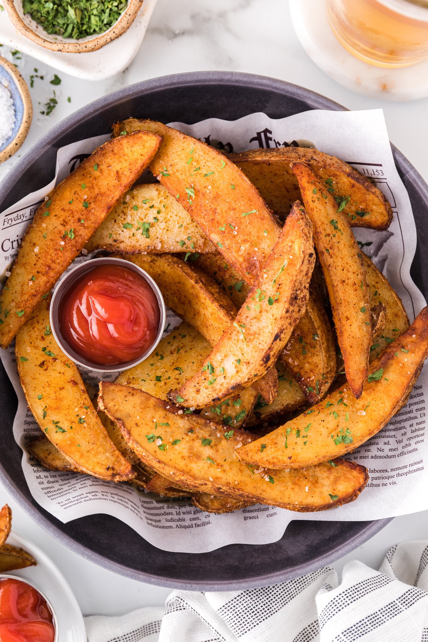 Air fryer potato wedges in a basket with ketchup.