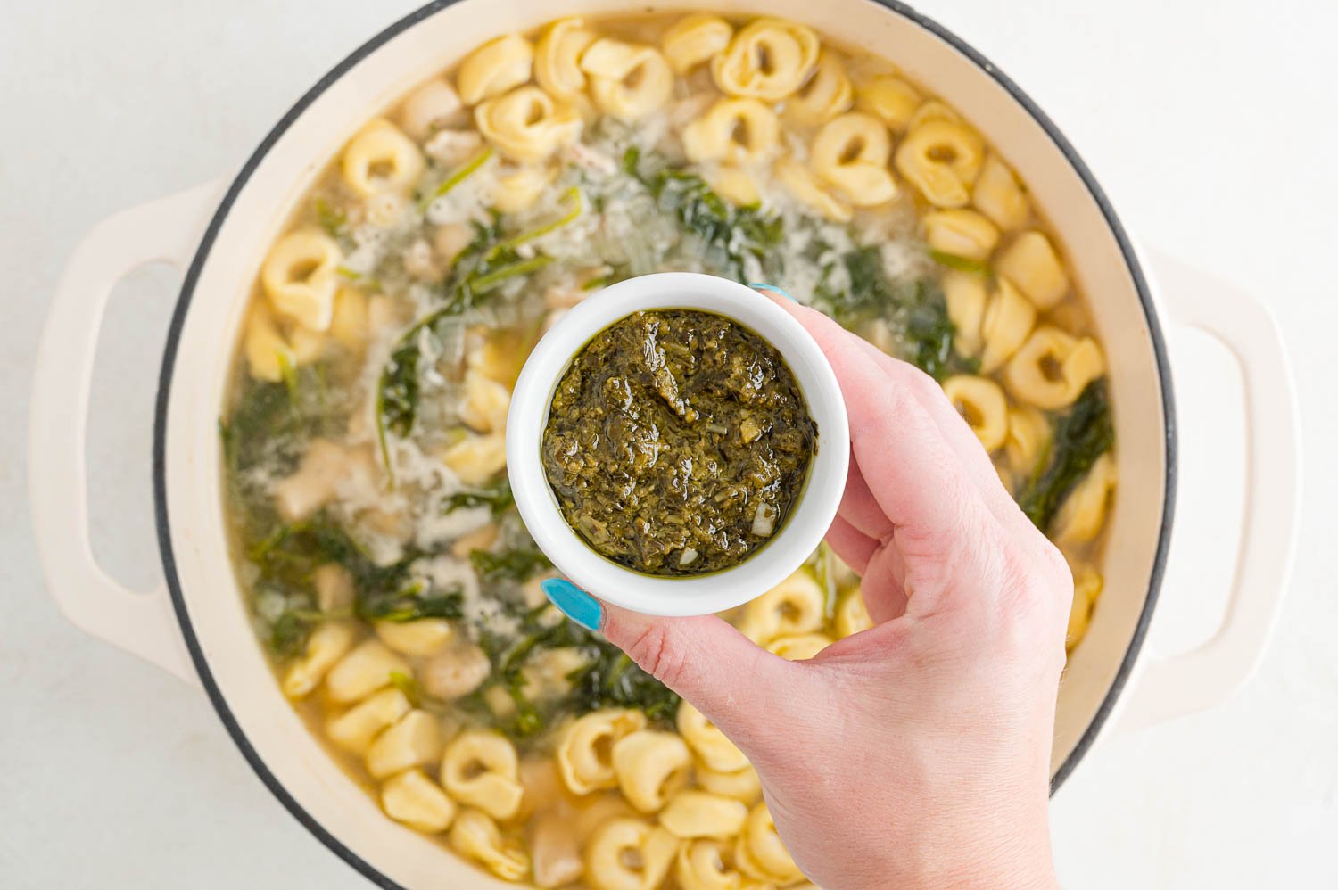 Pesto being added to soup.