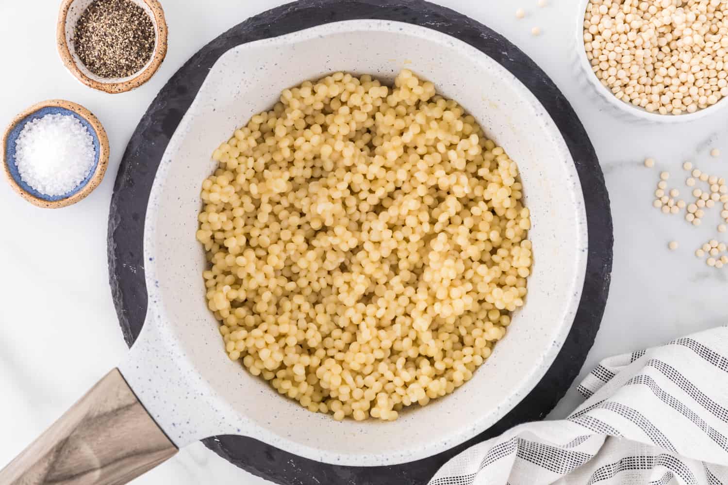 Pear couscous cooked and in a strainer.