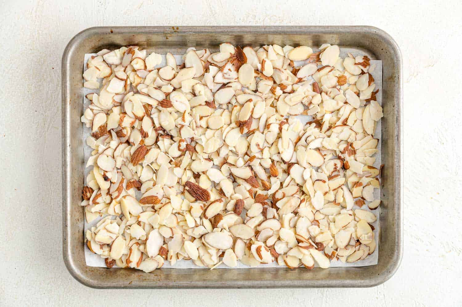 Toasting almonds is a great way to bring out their crunch and flavor. Learn how to toast almonds in the oven, microwave, and on the stovetop! Sliced almonds spread into an even layer on a parchment-lined baking sheet.