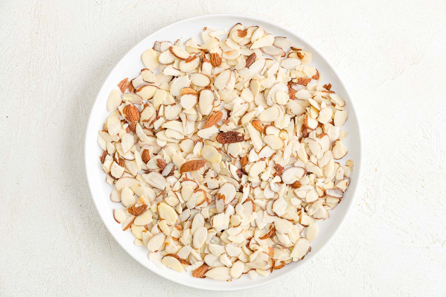 Sliced almonds on a white plate.