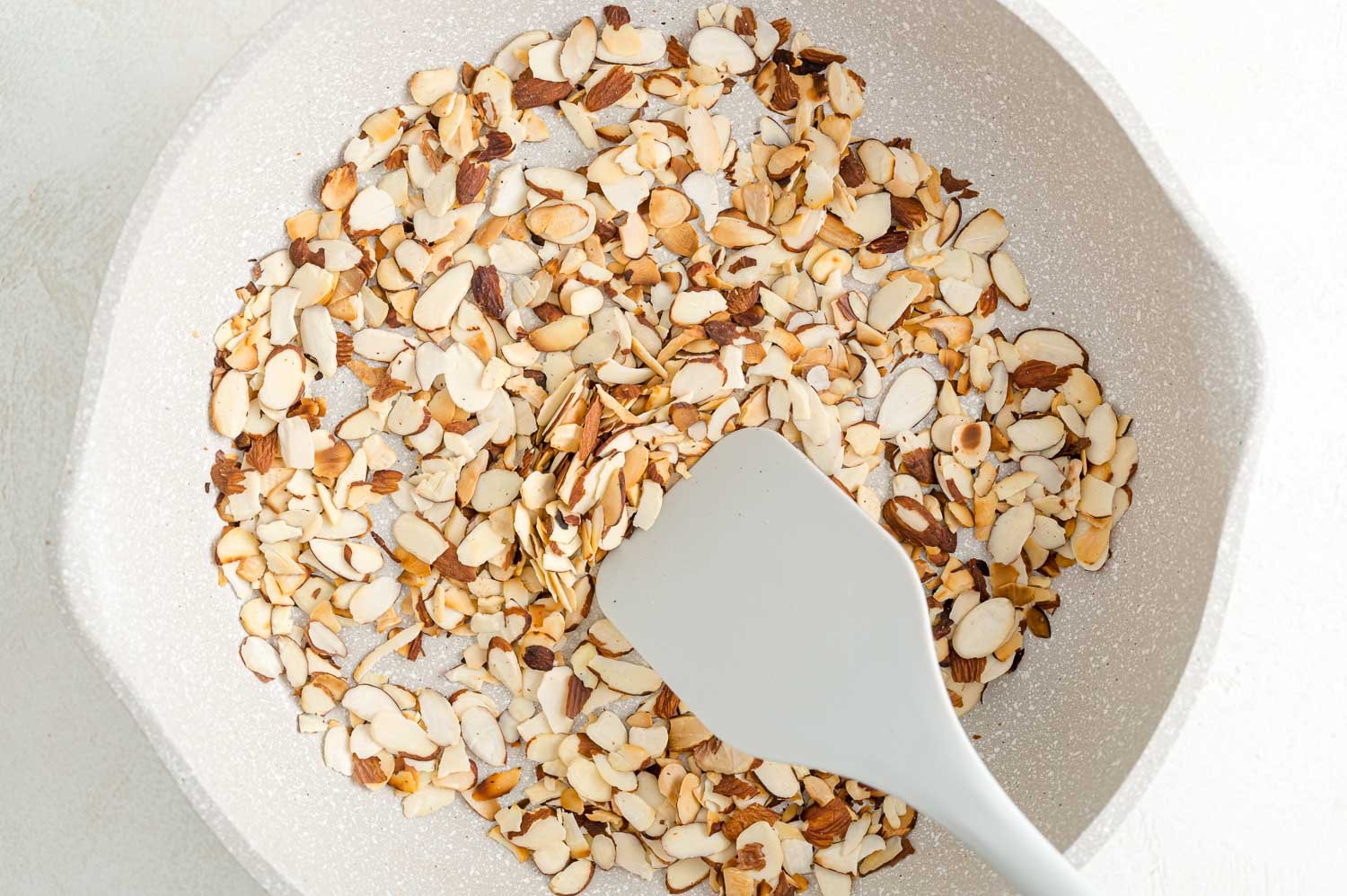 Toasting almonds is a great way to bring out their crunch and flavor. Learn how to toast almonds in the oven, microwave, and on the stovetop! A spatula stirring almonds as they toast in a skillet.