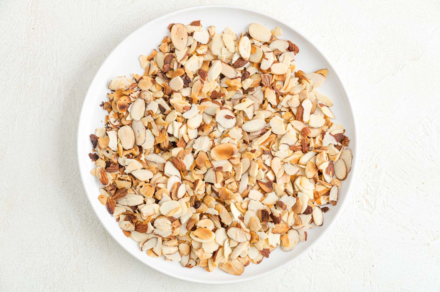 Toasted almond slices on white plate.