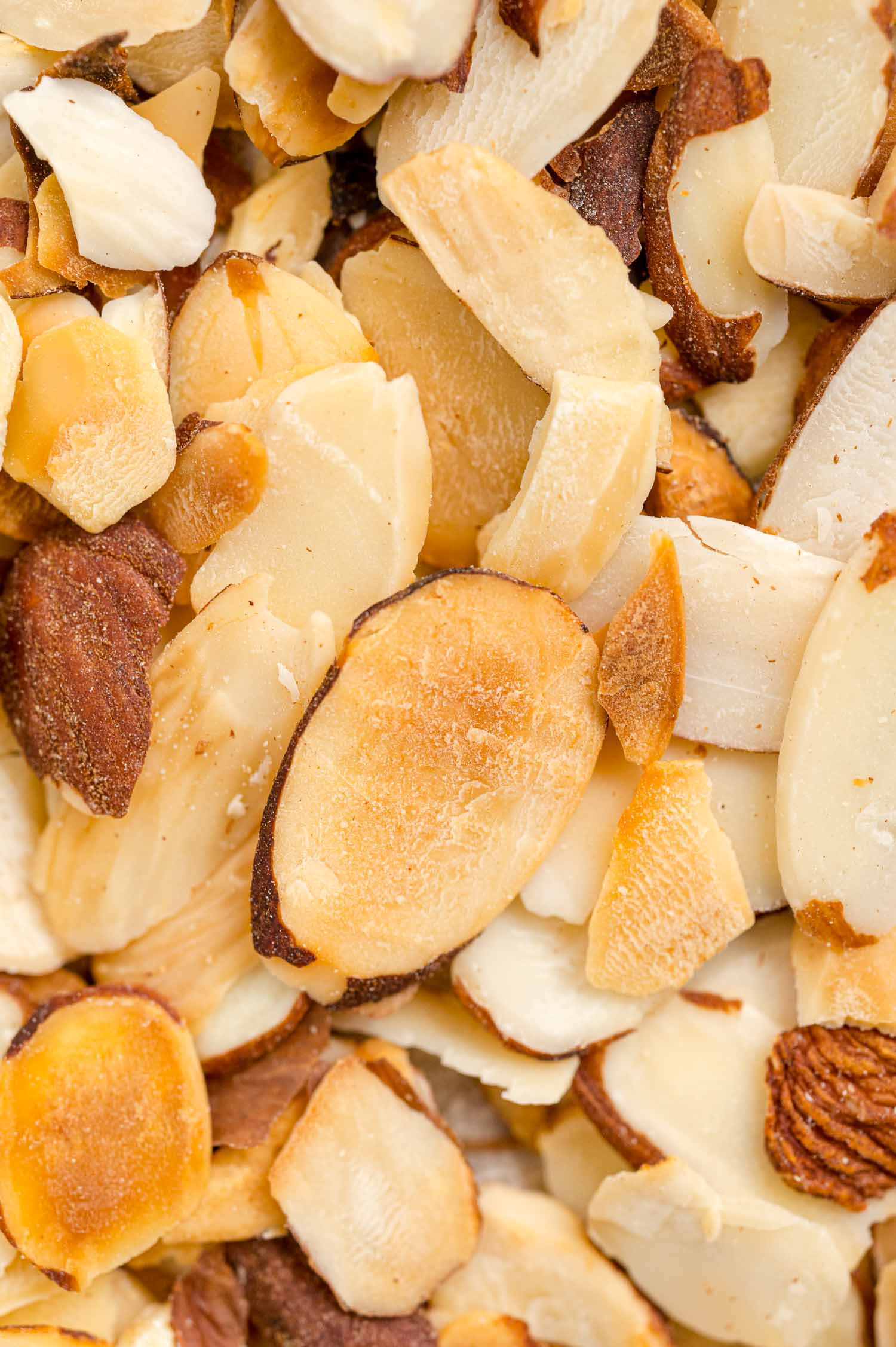 Toasting almonds is a great way to bring out their crunch and flavor. Learn how to toast almonds in the oven, microwave, and on the stovetop! Close up of toasted almond slices.