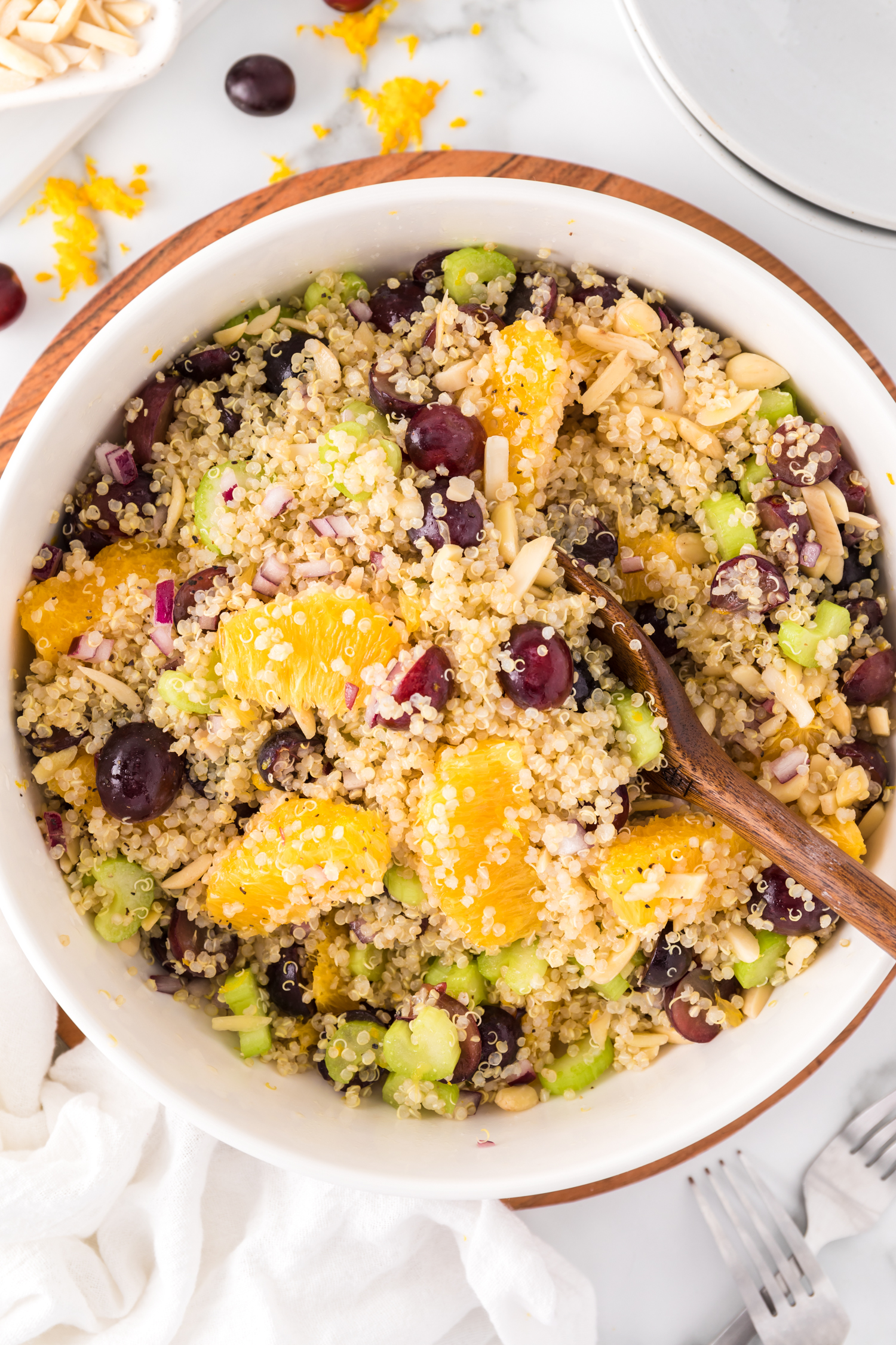 Quinoa salad in a large bowl, with oranges, grapes, almonds.