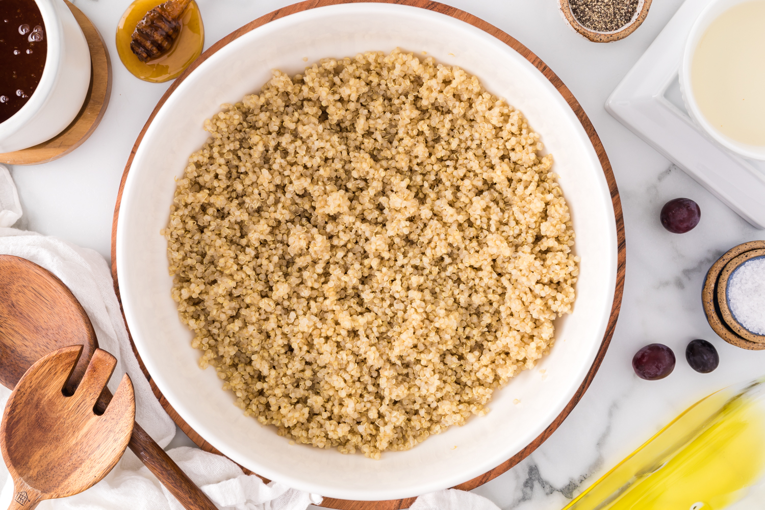 Quinoa in a large bowl, surrounded by other ingredients.