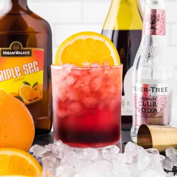 Red wine spritzer surrounded by ingredients.