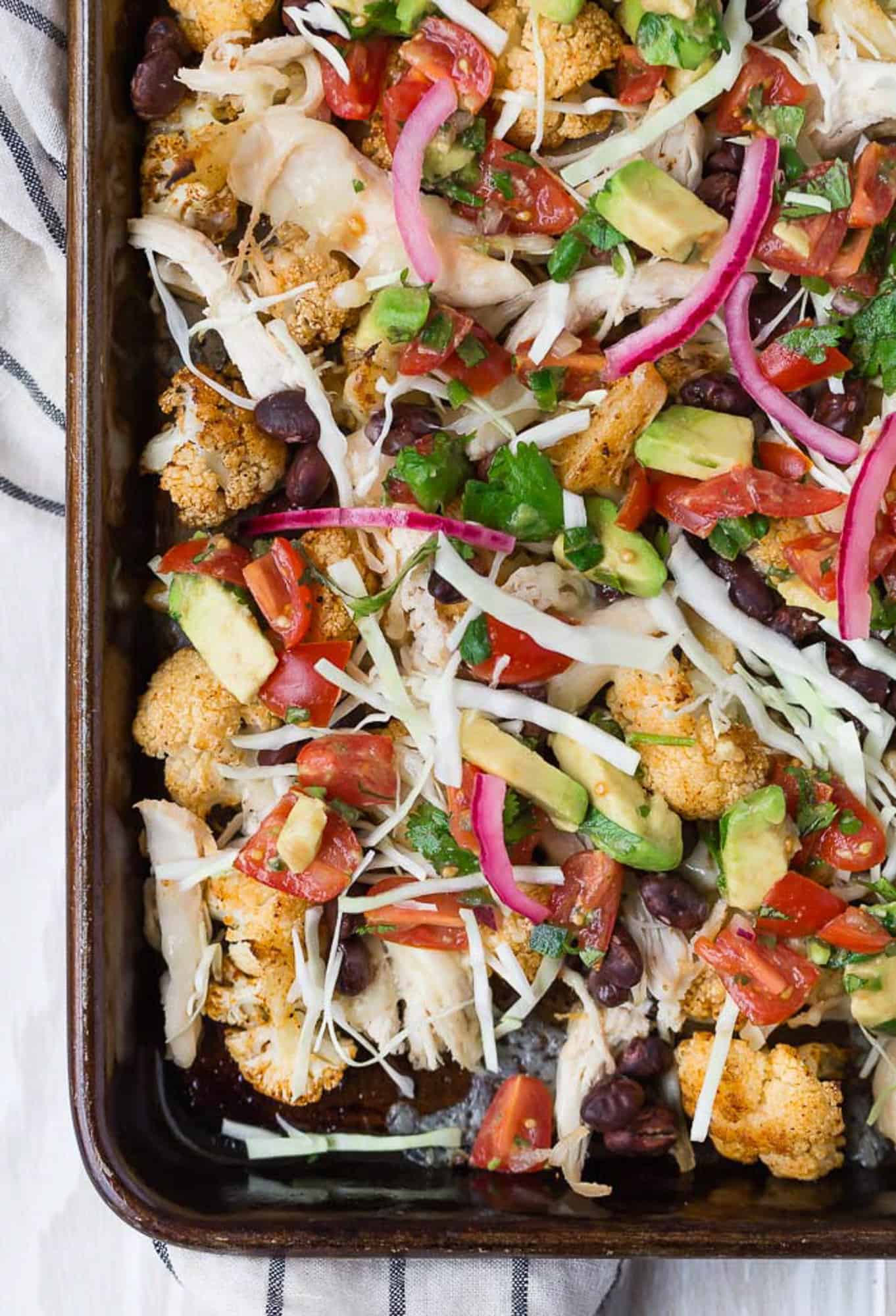 Nachos on sheet pan with assorted toppings.