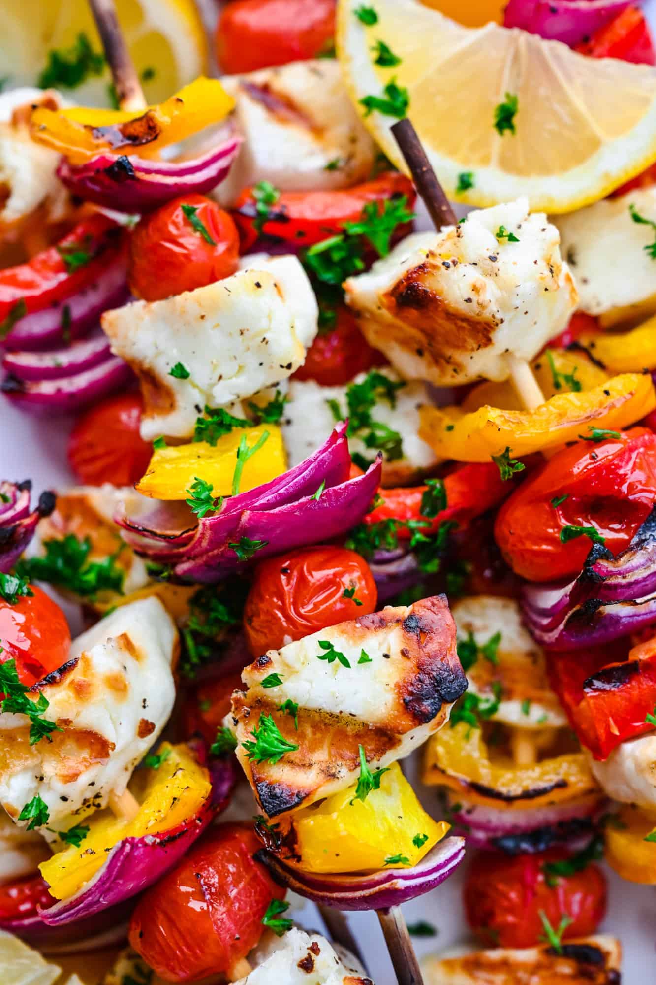 Close up of grilled halloumi and vegetables on kebabs.