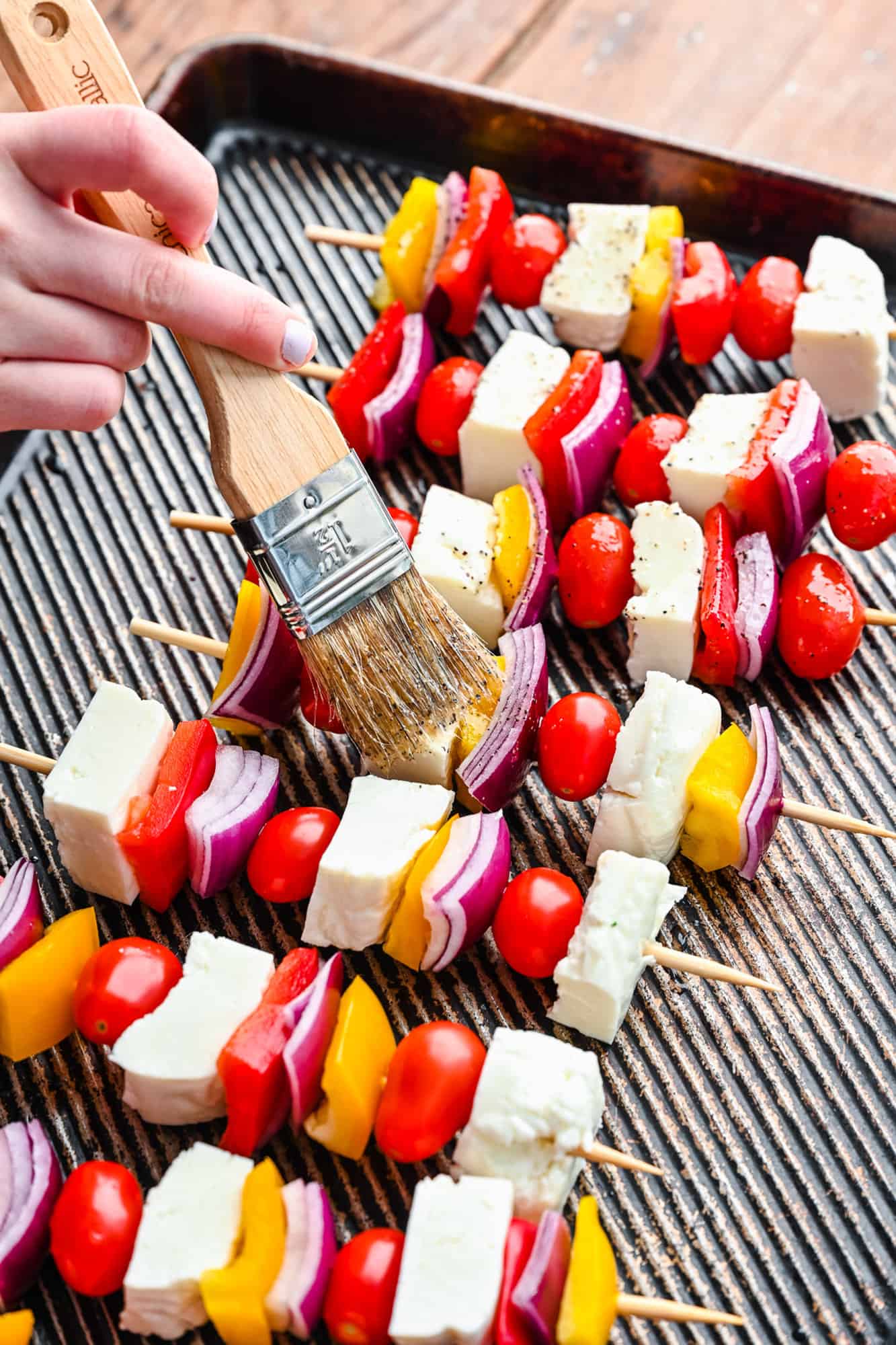 Kebabs being brushed with oil and lemon juice mixture.