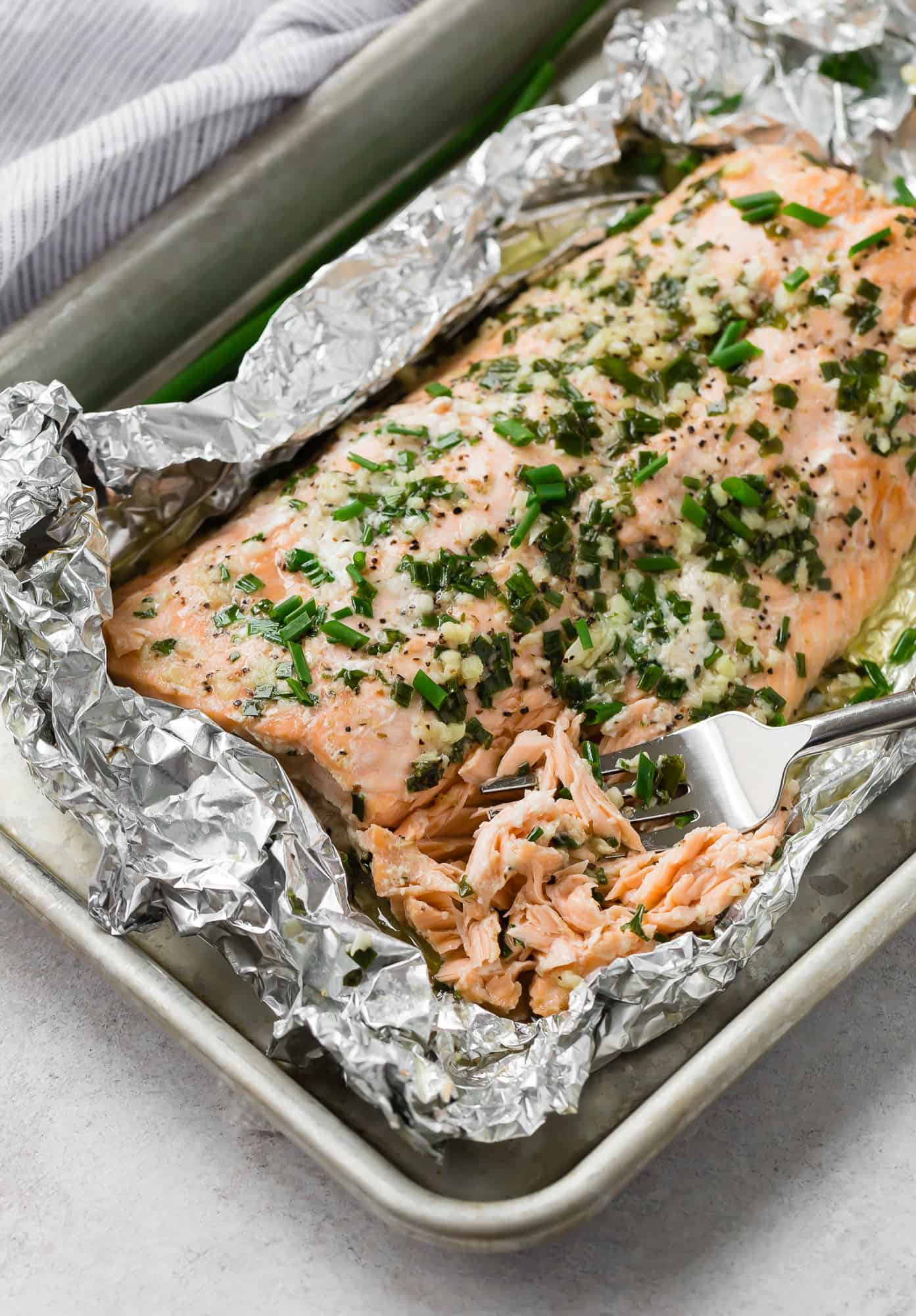 Chive topped salmon being flaked with a fork.