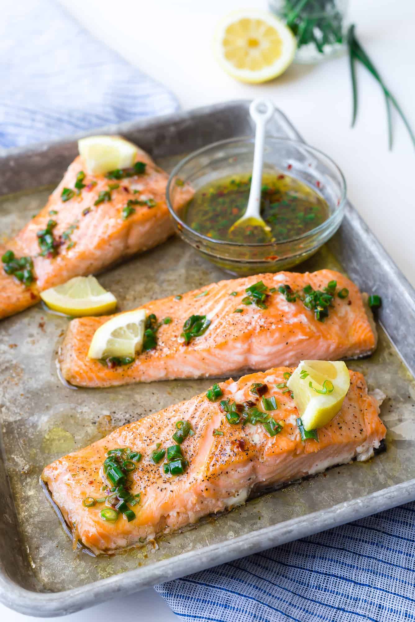 Salmon fillets on a sheet pan with lemon chive sauce.