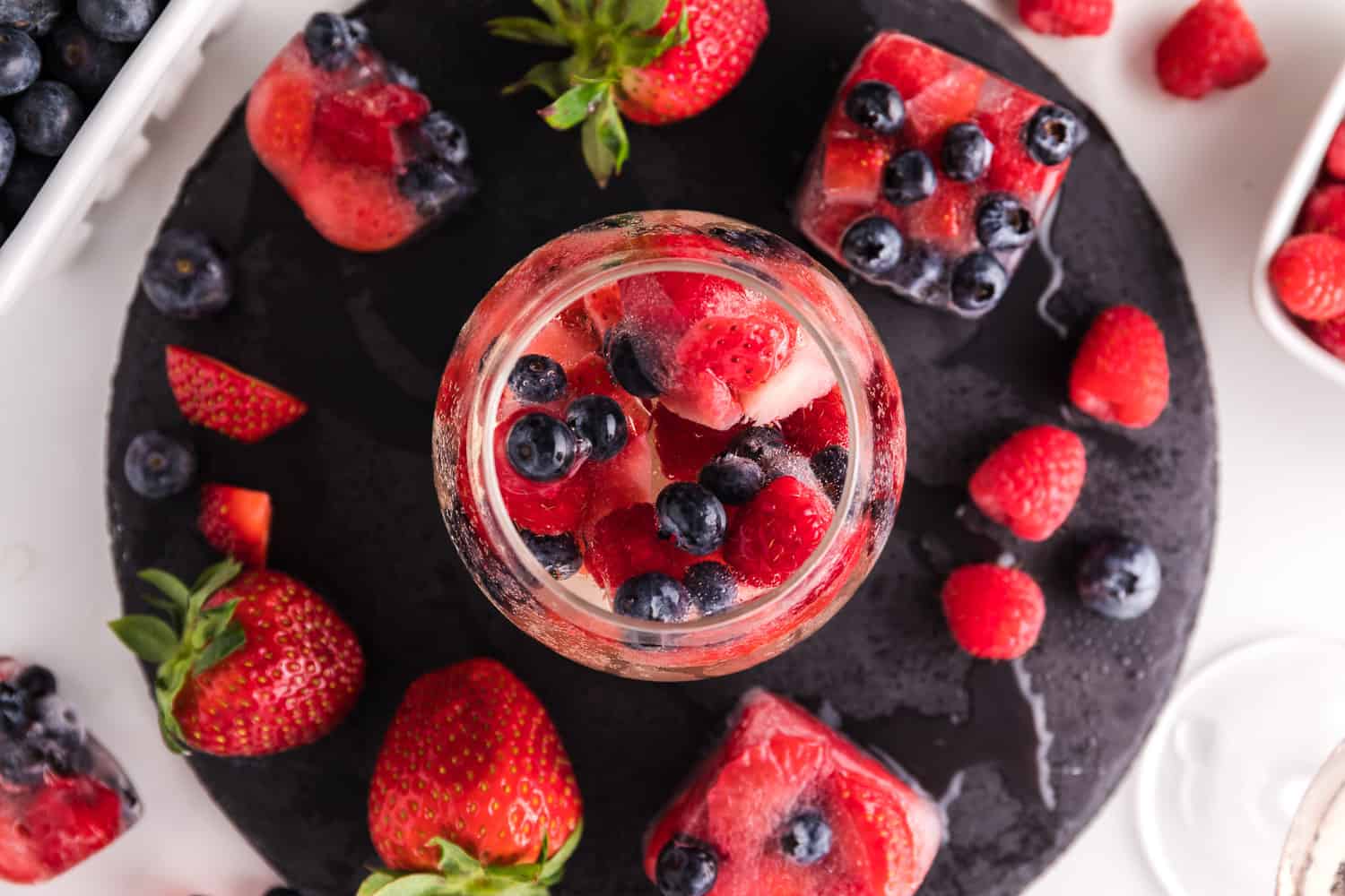 Spritzer surrounded by berries and ice cubes.