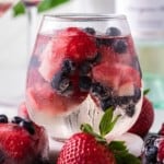 White wine spritzer with berry ice cubes.