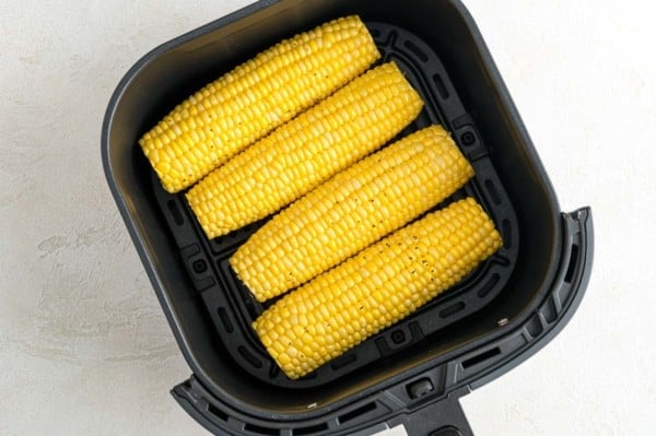 Four ears of corn inside the air fryer.