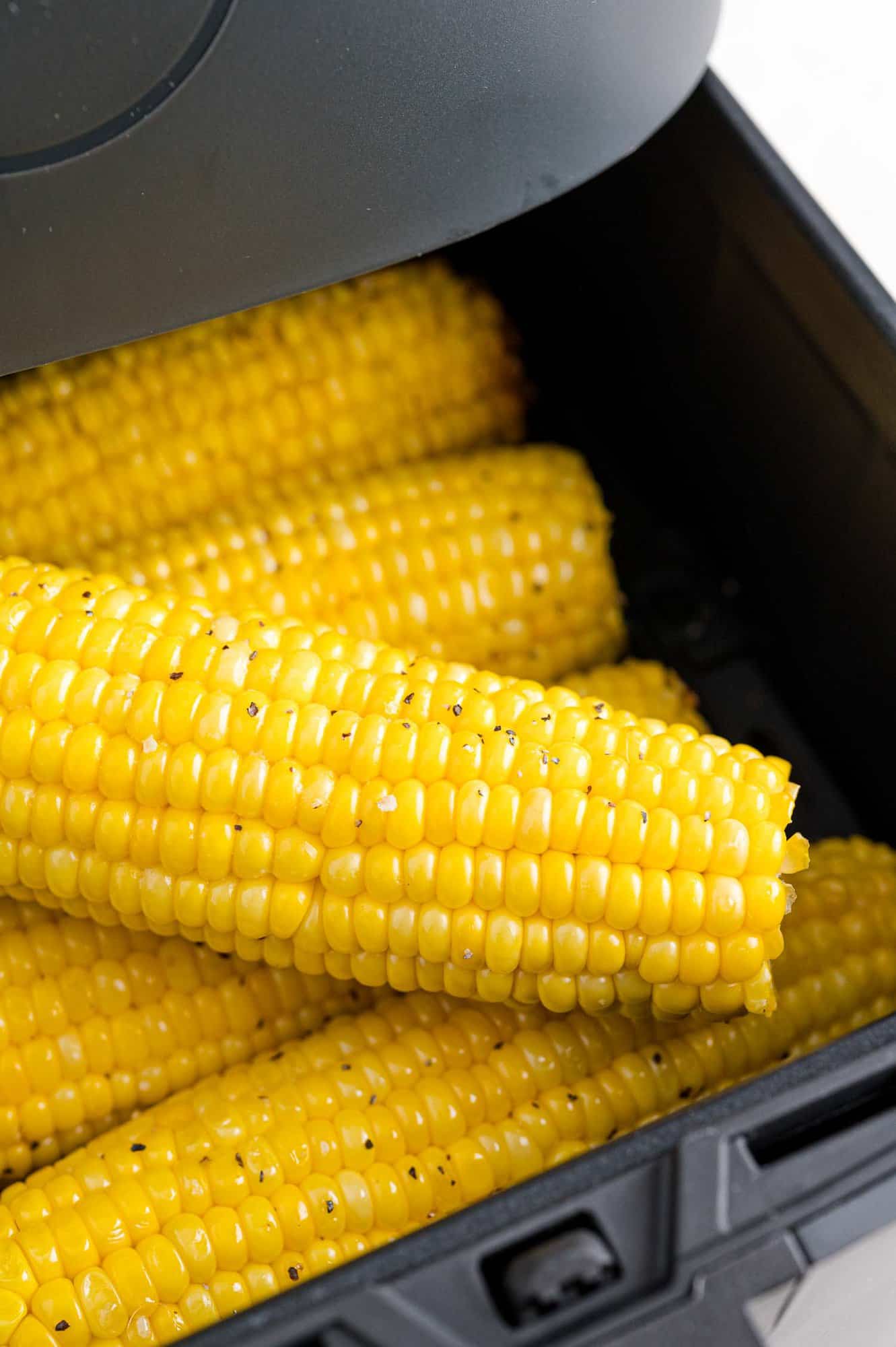 Air fryer corn on the cob inside the open air fryer basket.