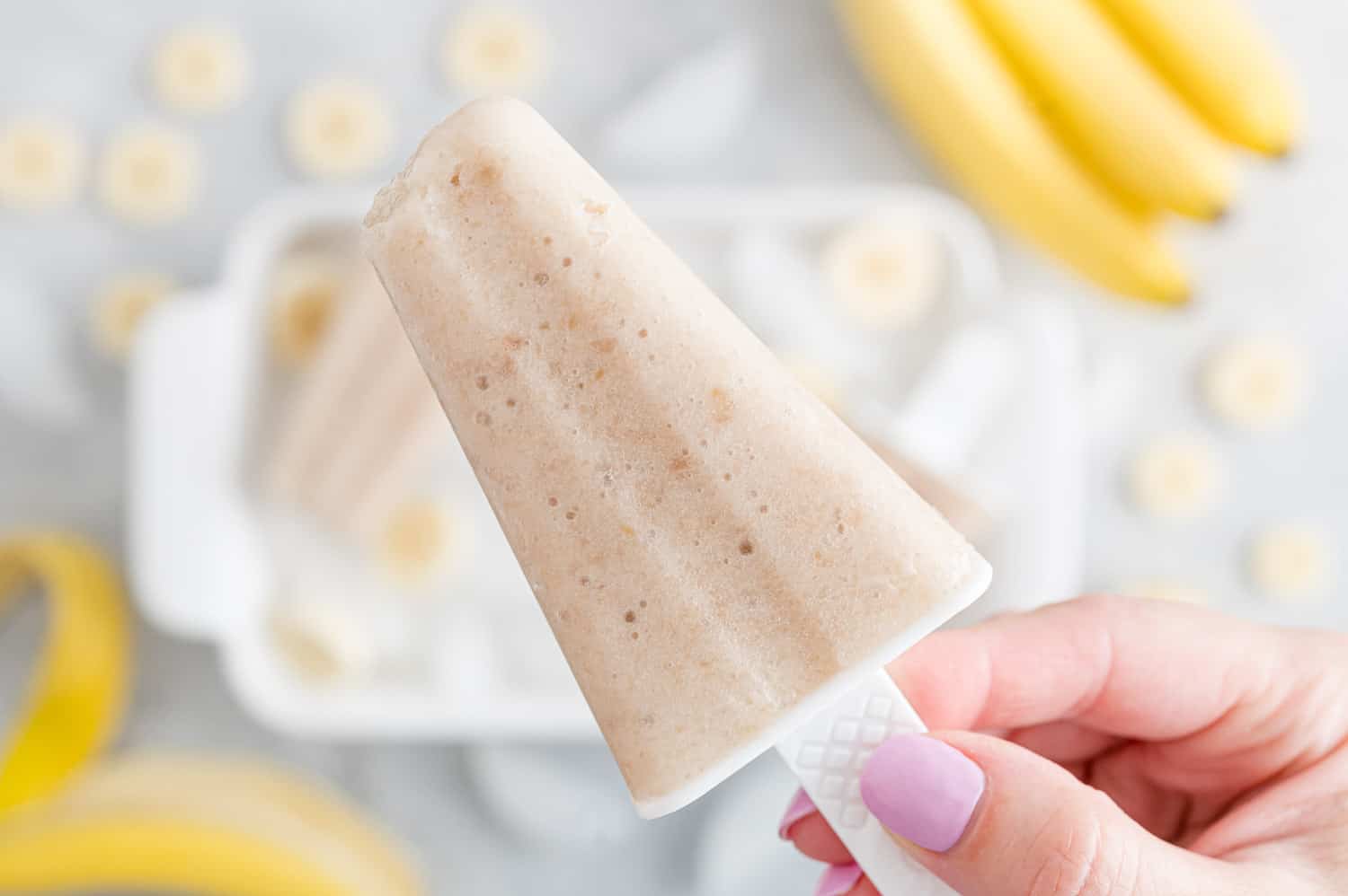 Natural banana popsicle held in a hand.